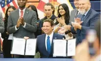  ?? RICH POPE/ORLANDO SENTINEL ?? Gov. Ron DeSantis holds up two house bills, HB 931 and HB 1317, after signing them on Thursday at Tohopekali­ga High School in Kissimmee.