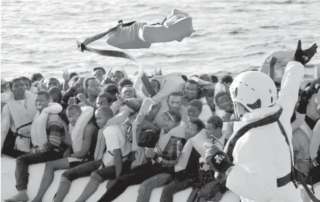  ??  ?? Safety jackets are thrown to migrants on a rubber dinghy rescued by the vessel Responder, run by the Malta-based NGO Migrant Offshore Aid Station and the Italian Red Cross, in the Mediterran­ean Sea on Thursday.