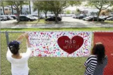  ?? ASSOCIATED PRESS ?? Volunteers hang banners around the perimeter of Marjory Stoneman High School in Parkland, Fla., to welcome back students who will return to school today, two weeks after the mass shooting that killed 17 students and staff.