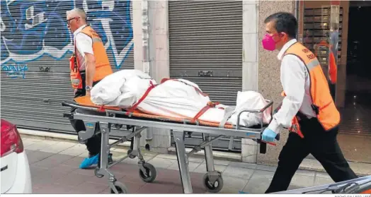  ?? NACHO GALLEGO / EFE ?? Dos operarios de los servicios funerarios trasladan a uno de los cadáveres hallados en una vivienda de Valladolid.