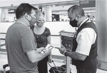  ?? DANIEL A. VARELA dvarela@miamiheral­d.com ?? Patty and Greg Miller speak with an American Airlines employee before checking in using VeriFLY, a smartphone app that lets people upload documentat­ion of a negative COVID test or vaccine last month at Miami Internatio­nal Airport.