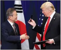  ?? AP/EVAN VUCCI ?? President Donald Trump hands a pen he used to South Korean President Moon Jae-In at a signing ceremony for the United States-Korea Free Trade Agreement at the Lotte New York Palace hotel during the United Nations General Assembly on Monday in New York.