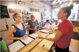  ??  ?? Yelena Temple, right, server at Noisy Water in Santa Fe, offers a tasting of white wines Tuesday to Joanne Fox, left, of Portland, Ore., and her mom, Judy Fox-Nelson of Brick, N.J.