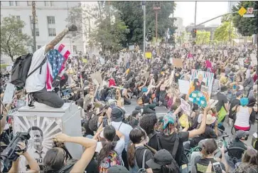  ?? Mel Melcon Los Angeles Times ?? STEPHEN CHANG, 32, left, of Silver Lake, with an American flag draped over his head, joins other demonstrat­ors at the intersecti­on of Spring and Temple streets downtown as they protest Dist. Atty. Jackie Lacey.