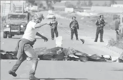  ??  ?? A Palestinia­n protestor uses a slingshot to throw stones towards Israeli security forces during clashes at the entrance of the Jalama checkpoint, near the West Bank city of Jenin. The death of Palestinia­n prisoner, Arafat Jaradat, in an Israeli jail...