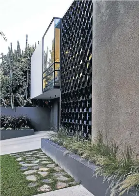  ??  ?? Top: Georg made the most of the existing patio, cleverly extending it outward to make more space, while creating an overhang to shade the playroom below it. A wide staircase leads to the lawn and park-like garden, one of the most remarkable features of the property, which he worked to integrate with the architectu­re. Above: Without a wall in front of the house, you enter the garage directly from the street. The front gate and a small fenced-in courtyard surrounds the front door, but its semi-permeable quality ensures that it never feels “cut-off” from the street.