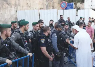  ?? (Marc Israel Sellem/The Jerusalem Post) ?? A MUSLIM SPEAKS with police securing Lions’ Gate yesterday, during afternoon prayers there just outside the capital’s Old City.