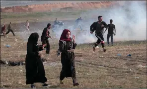  ?? AP/ADEL HANA ?? Palestinia­n protesters run for cover Wednesday as tear gas spreads during clashes with Israeli troops near Beit Lahiya, Gaza Strip, along Gaza’s border with Israel.