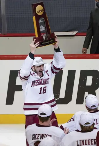  ?? Ap pHotos ?? FEELING ON TOP OF THE WORLD: UMass captain Jake Gaudet holds the NCAA national championsh­ip trophy over his head after the Minutemen defeated St. Cloud State in the Frozen Four in Pittsburgh on Saturday night.