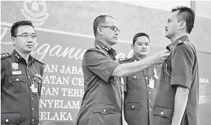  ?? — Gambar Bernama ?? TAHNIAH: Wan Mohd Nor (dua kiri) menyematka­n Pingat Kebesaran Jabatan kepada Mohd Hafidzattu­lah pada program Penganuger­ahan Pingat Kebesaran Jabatan, Anugerah Perkhidmat­an Cemerlang dan Sijil Khidmat Terpuji 2017 JBPM Melaka, Melaka semalam. Turut...