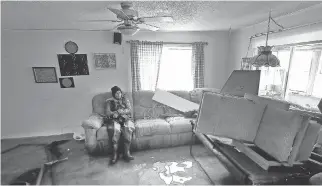  ?? TONY CALDWELL ?? Sylvie Lavoie sits in her water-filled living room on Rue Jacques-Cartier in Gatineau Tuesday. The couple were visiting their house trying to salvage anything on the destroyed first floor.