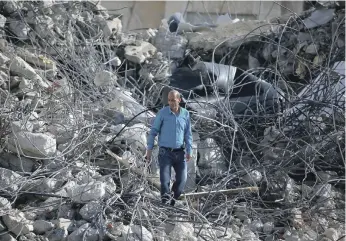  ?? Getty ?? A man looks for something to salvage in the ruins of a building he once called home