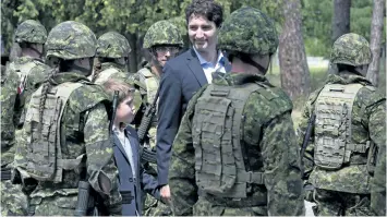  ?? ADRIAN WYLD/ THE CANADIAN PRESS ?? Prime Minister Justin Trudeau and his son Xavier review an honour guard as they arrive at the Internatio­nal Peacekeepi­ng and Security Centre in Yavoriv, Ukraine in 2016. Trudeau has finally unveiled Canada’s long- awaited commitment to United Nations...