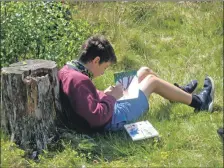  ??  ?? A pupil enjoys the sunshine while painting a nature scene.