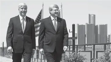  ?? GOVERNMENT OF CANADA ?? Prime Minister Stephen Harper, right, and Michigan Governor Rick Snyder walk along the Windsor riverfront with Detroit in the background before an announceme­nt about the new bridge on June 15.