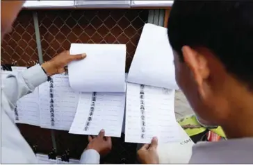  ?? PHA LINA ?? People search for their names on the NEC voter lists in Phnom Penh’s Tonle Bassac commune in January this year.