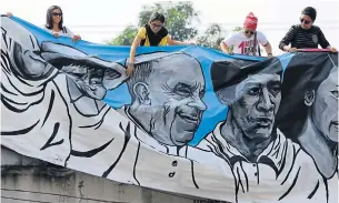  ?? AP ?? Filipino activists unfurl a painting with an image of Pope Francis as they prepare to welcome him during his arrival in Manila yesterday.