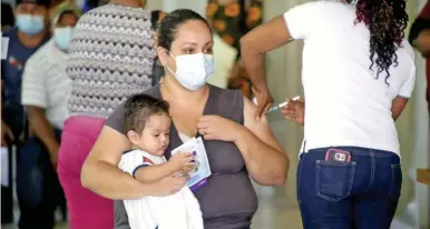  ?? ?? INMUNIZACI­ÓN. Una madre recibe su vacuna en la terminal de buses de San Pedro Sula.