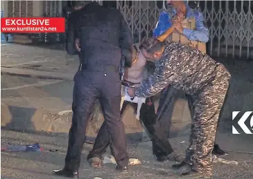  ?? KURDISTAN 24 TV/AP ?? In this still from local TV footage, a child is restrained by security forces as another man cuts off a belt of explosives on Sunday, in Kirkuk, Iraq. Militants in several countries are deploying child suicde bombers with devastatin­g results.