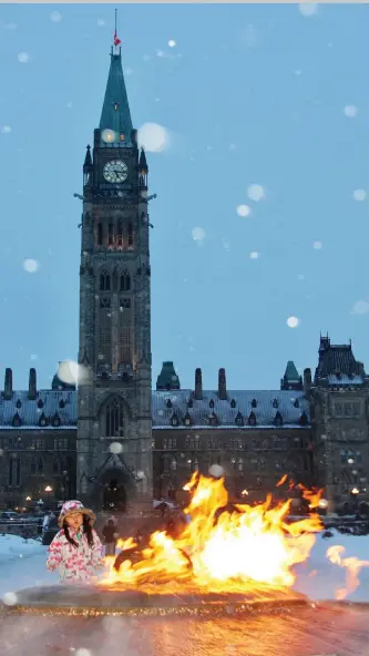  ??  ?? Journey Froese warms up by the Centennial Flame on Parliament Hill in Ottawa.