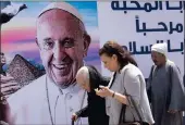  ??  ?? People walk past a billboard welcoming Pope Francis in Cairo on Thursday.