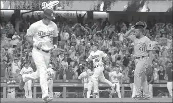  ?? AP/MARK J. TERRILL ?? Los Angeles’ Cody Bellinger (left) runs to first as Chase Utley (center) heads in to score after Kansas City’s Kelvin Herrera (right) walked in the winning run in the 10th inning Saturday in Los Angeles.