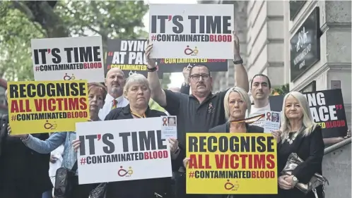  ?? ?? Demonstrat­ors hold placards reading message related to the NHS infected blood scandal