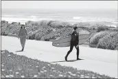  ?? ERIC RISBERG — THE ASSOCIATED PRESS FILE ?? A surfer walks across the car-free Great Highway toward the ocean in San Francisco. At the start of the pandemic, San Francisco closed off parts of a major beachfront highway and Golden Gate Park to cars so that people had a safe place to run and ride bikes. Open space advocates want to keep those areas car-free.