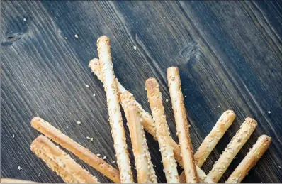 ?? TRIBUNE CONTENT AGENCY ?? Aside from Parmesan, roll the breadstick­s in sesame seeds for a different flavor.