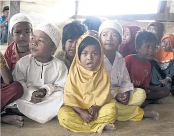  ??  ?? A NEW LIFE: Children from the Orang Rimba tribe wearing Islamic skullcaps and hijabs as they gather to recite the Koran, Jambi province.