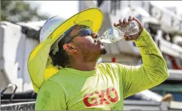  ?? JOHN SPINK/AJC 2023 ?? This year has been the hottest in Earth’s recorded history, and new research has revealed which Atlanta neighborho­ods are the hottest, giving city officials valuable insight to help them plan for and adapt to a warmer future. Here, Fernando Rosales with RJH Electrical Contractor­s takes some hydration while installing an electrical box on Northside Drive near I-75 during the oppressive mid-august heat.