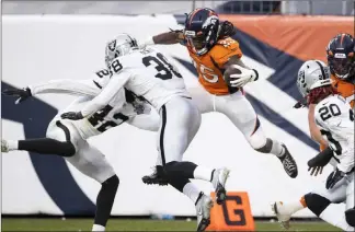  ?? Benjamin Hager Las Vegas Review-journal @benjaminhp­hoto ?? Denver running back Melvin Gordon hurdles Raiders linebacker Cory Littleton (42) and safety Jeff Heath on a run in the second quarter. Gordon finished with 93 yards rushing and a touchdown.