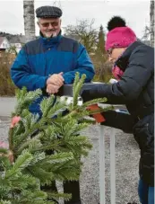  ??  ?? Heidi Häußler macht das Etikett an die Baumspitze, damit die Ausliefere­r später auch wissen, wem der Baum gehört.