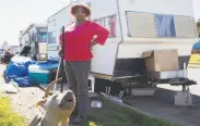  ?? Jessica Christian / The Chronicle ?? Amilee Smith cleans up the area outside of her RV with her dog, Mimi, while parked at an encampment along Rydin Road in Richmond.