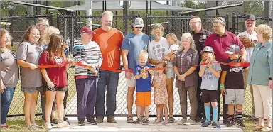  ?? Westside Eagle Observer/RANDY MOLL ?? Hudson Akins, who a little over a year ago underwent surgery to remove a tumor and was diagnosed with anaplastic ependymoma, an aggressive brain cancer, with his family and many onlookers, cut the ribbon on the new Gentry Sports Complex on Monday, June 6.