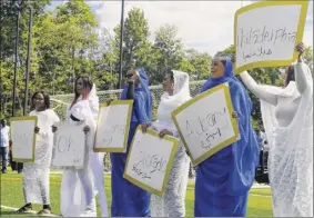  ??  ?? Women hold up signs representi­ng teams at the Sudanese American Soccer federation tournament on Saturday.