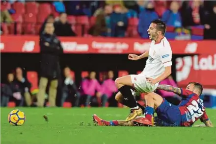  ?? AFP PIC ?? Sevilla’s Pablo Sarabia (left) is tackled by Levante’s Antonio Luna in a La Liga match at the Ramon Sanchez Pizjuan Stadium on Friday.