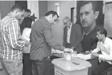  ?? SANA via Associated Press ?? ■ In this photo released by the Syrian official news agency SANA, Syrians cast their votes Sunday at a polling station during municipal elections in Damascus, Syria. Syria is holding its first municipal elections since 2011 amid tensions with the country’s self-administer­ed Kurdish region, which is refusing to allow polls.