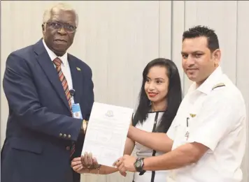  ??  ?? Director General of the Guyana Civil Aviation Authority (GCAA) Lieutenant Colonel (Ret’d) Egbert Field (left), hands over the certificat­ion to Chief Executive Officer of Domestic, Orlando Charles and his wife Komal Devi Charles.