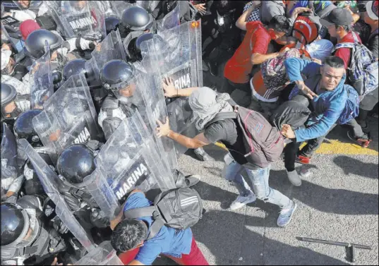  ?? Marco Ugarte The Associated Press ?? Migrants charge on Mexican National Guardsmen on Saturday at the border crossing between Guatemala and Mexico in Tecun Uman, Guatemala. Thousands of Central American migrants surged onto a bridge at the border between the two countries.