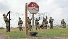  ?? JOHN MOORE/GETTY IMAGES ?? U.S. Army soldiers from Fort Riley, Kan., string razor wire near the port of entry at the U.S.-Mexican border Nov. 4 in Donna, Texas.