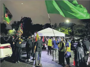  ??  ?? In a photo provided by Fatima Mukhi-Siwji, people gather with flags in a parking lot for a drive-in commemorat­ion of the seventh-century death of Imam Hussein, Thursday, Aug. 27, 2020, in Hicksville, N.Y. Shiite Muslims are marking the mourning period in the shadow of the coronaviru­s. (Fatima Mukhi-Siwji via AP)(Fatima Mukhi-Siwji via AP)