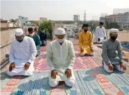  ?? — S. SURENDER REDDY ?? Muslims offer Id prayers on their terrace maintainin­g social distancing and wearing masks at Begumpet on Monday.