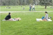  ??  ?? Olivia Brownson, left, and her friend Justine Slosson, right, with her dog Sophie, practice good social distancing Sunday while catching up with one another at Cheesman Park. Denver has closed three streets to give citizens more room to get outside.