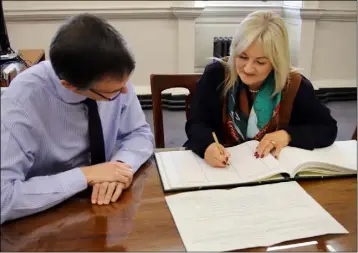  ??  ?? Verona Murphy signing the roll in Dáil Eireann, accompanie­d by Clerk of the Dáil, Peter Finnegan.