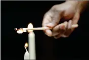  ?? ASSOCIATED PRESS ?? COREY CAVER LIGHTS CANDLES before the Friday Shabbat Service at KAM Isaiah Israel in Chicago. On the eve of the day set aside to honor an African American who strove against hate and preached racial and social justice, some worry the nation is becoming more divided.