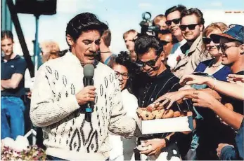  ?? COLORADOAN ARCHIVE ?? Geraldo Rivera gives a crowd doughnuts outside of Debbie Duz Donuts as he films a segment for his show Geraldo, which aired in early November 1989.