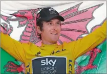  ?? CHRISTOPHE ENA/AP PHOTO ?? Britain’s Geraint Thomas, wearing the overall leader’s yellow jersey, holds the Welsh flag on the podium after the twentyfirs­t stage of the Tour de France on Sunday on Champs-Elysees avenue in Paris.