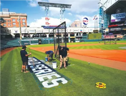  ?? AP PHOTO/DAVID J. PHILLIP ?? Stadium workers paint the logo on the field Monday in Houston in preparatio­n for Game 1 of the World Series between the Houston Astros and the Atlanta Braves.