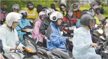  ?? — AFP ?? Motorcycli­sts clad in rainjacket­s and ponchos ride to work in Taipei as tropical storm Haitang hits Taiwan on Monday.